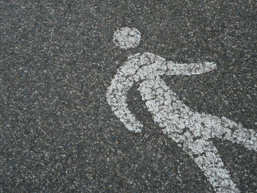 A baseball rests beside a lifted roof shingle with scattered granules visible on the surface.
